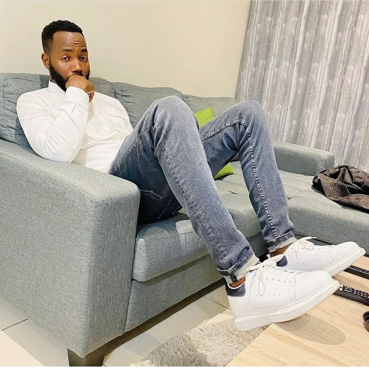 Menzi Biyela in a white shirt and jeans, relaxed lounge portrait
