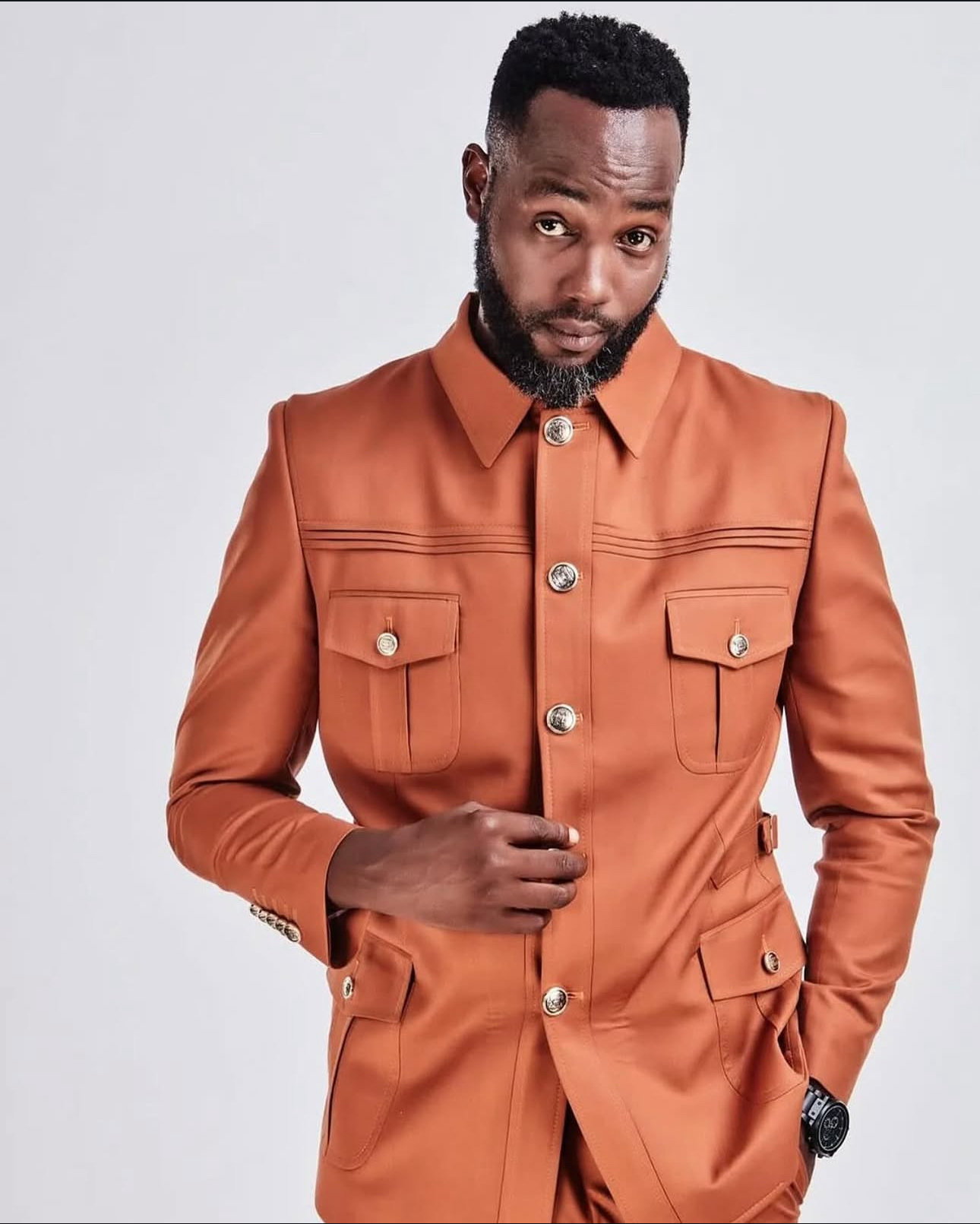 Menzi Biyela in a terracotta safari-style suit, studio portrait